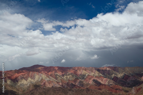 Enchanting mountain range. Panorama view of the popular Horoncal mountains in Humahuaca, Jujuy, Argentina. The colorful rock texture and pattern under a blue sky with clouds.