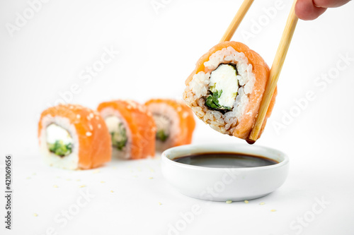take philadelphia maki rolls with bamboo chopstick on white background