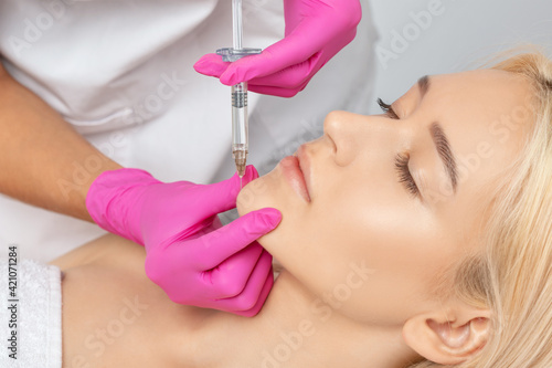 Cosmetologist makes rejuvenating anti wrinkle injections on the face of a beautiful woman. Female aesthetic cosmetology in a beauty salon. photo