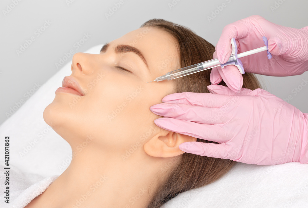 Cosmetologist makes rejuvenating anti wrinkle injections on the face of a beautiful woman. Female aesthetic cosmetology in a beauty salon.