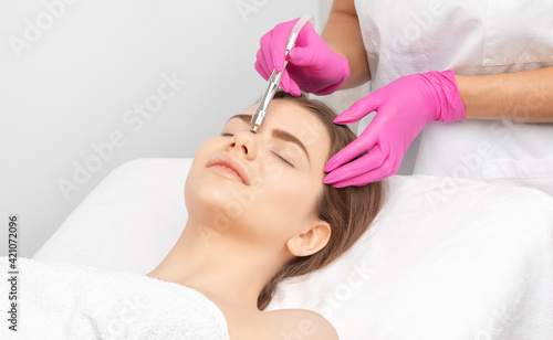 The cosmetologist makes the procedure Microdermabrasion of the face skin of a beautiful girl in a beauty salon.Cosmetology and professional skin care.