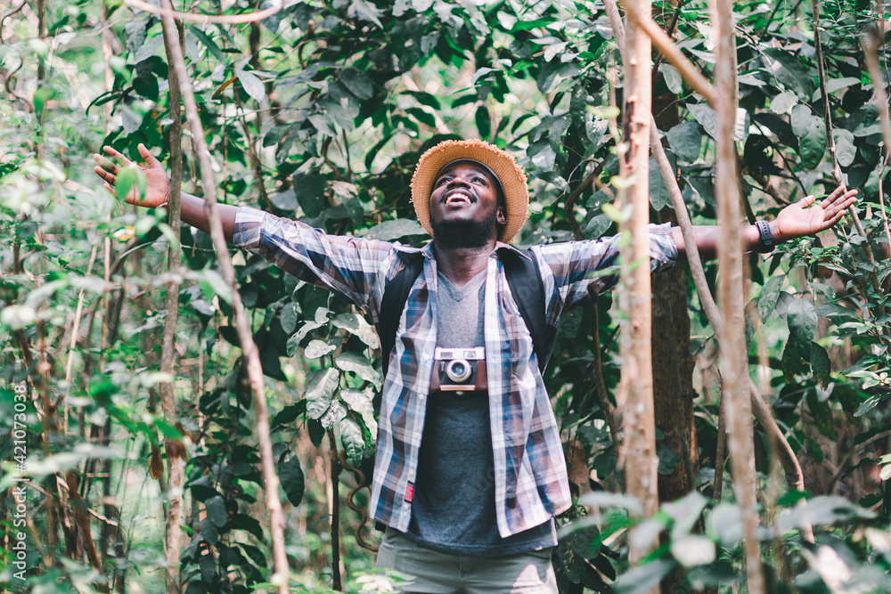 Happiness African man traveler with backpack walking  in the forest