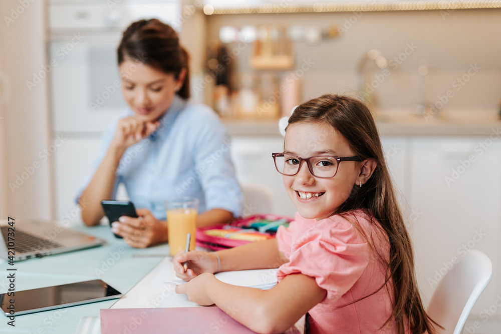 Mother works from home due to coronavirus while her daughter does her homework. Mother works from home due to coronavirus while her daughter does her homework.