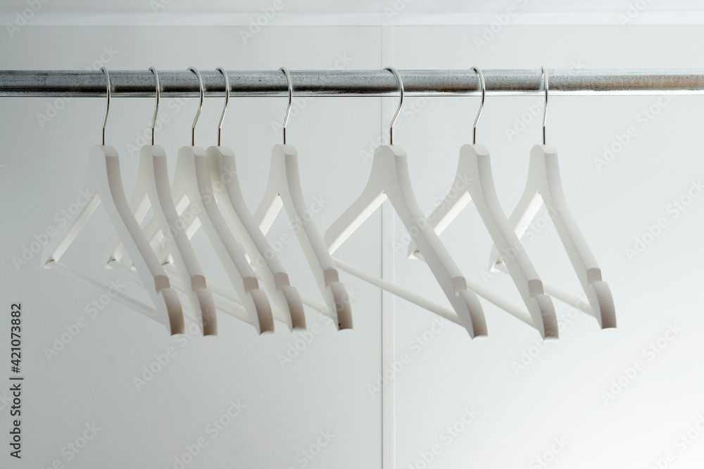 Empty clothes hangers, closeup. Modern new white closet. Many wooden white hangers on a rod. Empty clothes hangers, closeup. Modern new white closet. Many wooden white hangers on a rod.