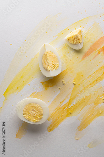 sliced chicken egg, on the background of yellow watercolor blot on white background, food photo art