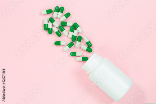 Yogurt capsules in a glass bottle on light pink background with copy space for your text. White probiotics capsules in pink background. Template medical blog social media. © banjongseal324