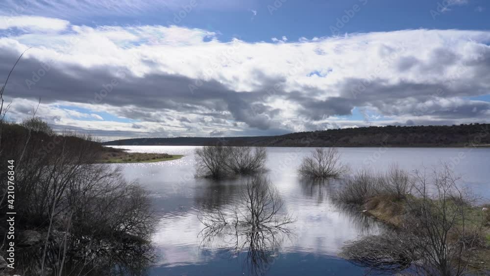 Lake landscape with plants and trees in the water, dark clouds and reflections of the sun in the water. Madrid Guadalix. Lake landscape with plants and trees in the water, dark clouds and reflections of the sun in the water. Madrid Guadalix.