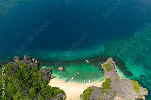 Fototapeta Naklejka Na Ścianę i Meble -  Aerial view of small isolated tropical island with white sandy beach and blue transparent water and coral reefs.