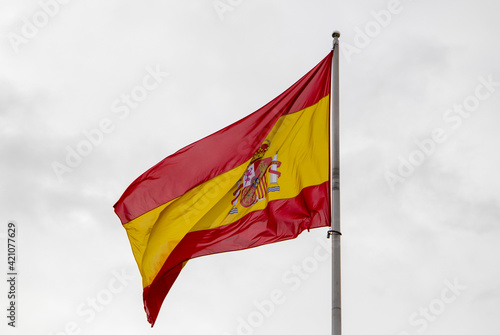 Flag of Spain waving on white sky.