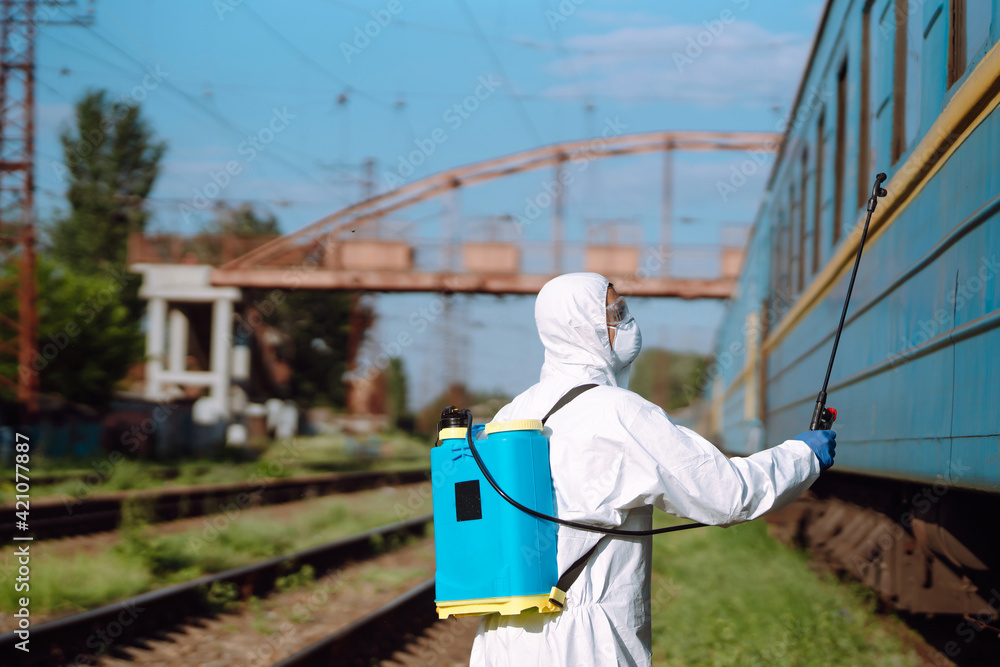 A man in a protective suit disinfects a train. Young man spraying disinfectant on public transportation. Covid-2019. Prevention of spreading global virus. A man in a protective suit disinfects a train. Young man spraying disinfectant on public transportation. Covid-2019. Prevention of spreading global virus.