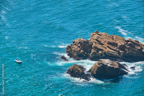 Fisherman in wetsuit at his dangerous work farming goose barnacles on the cliffs of cape tourinan, PORTUGAL © Daniel