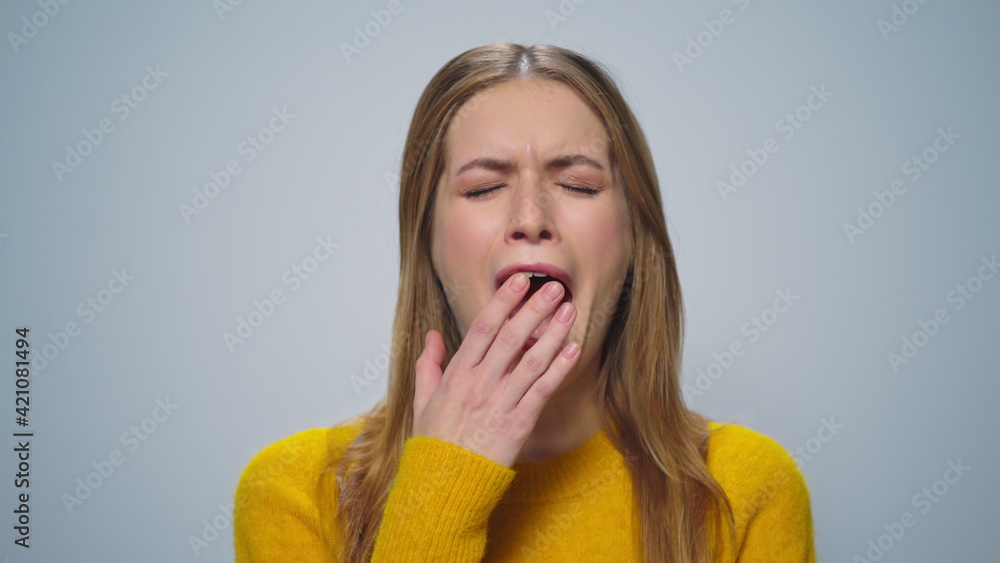 Portrait of smiling woman yawning at camera on grey background in studio. Portrait of smiling woman yawning at camera on grey background in studio.