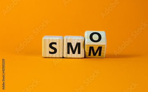 SMM vs SMO symbol. Turned a cube and changed words 'SMM, social media marketing' to 'SMO, social media optimization'. Business, SMM vs SMO concept. Beautiful orange background, copy space. photo