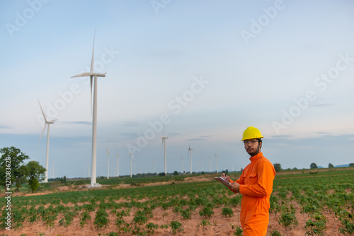 Silhouette of man engineer working and holding the report at wind turbine farm Power Generator Station on mountain,Thailand people