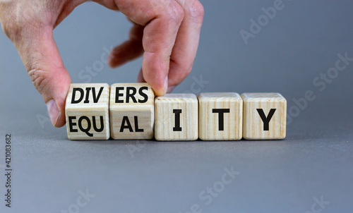 Diversity and equality symbol. Businessman turns wooden cubes, changes the word 'equality' to 'diversity'. Beautiful grey background. Business, diversity and equality concept. Copy space.