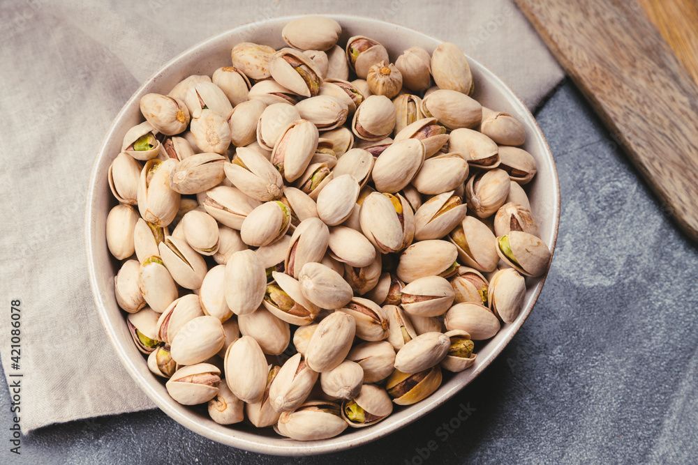 Ceramic bowl with pistachio nuts on linen tea towels Ceramic bowl with pistachio nuts on linen tea towels