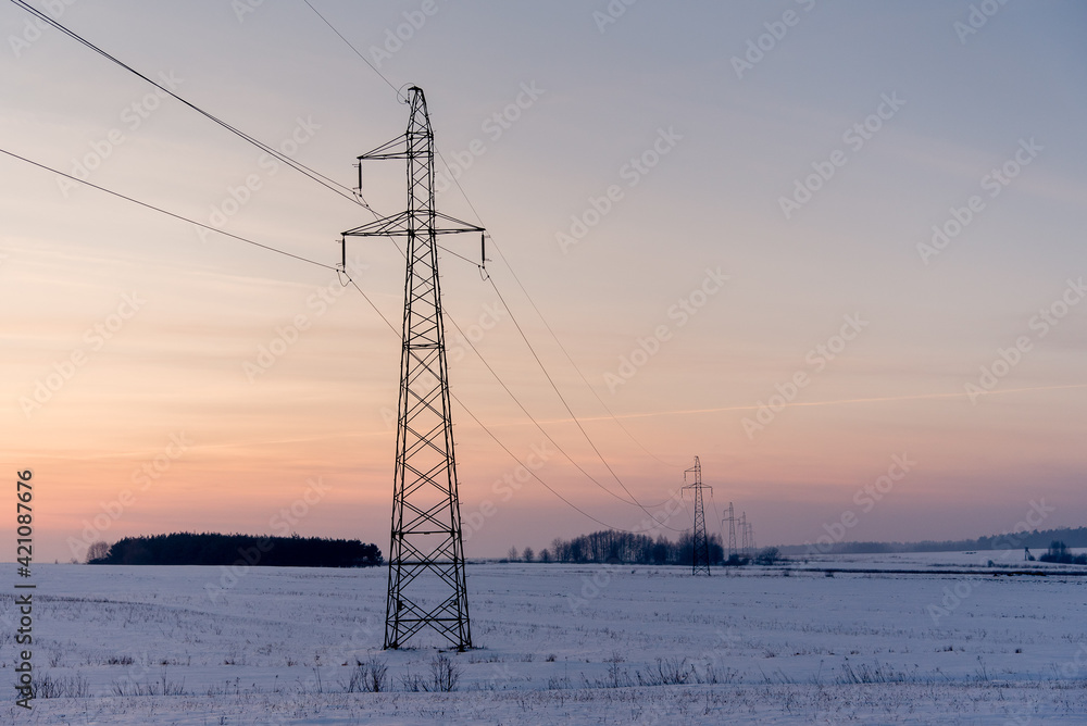 Hi-voltage electric power lines in a wintry foggy landscape.