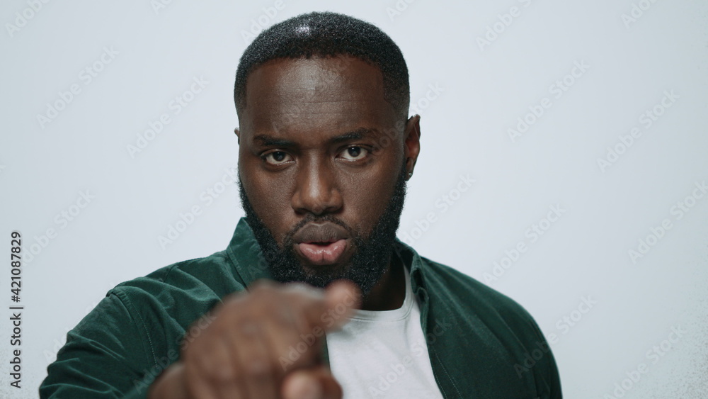 Portrait of serious african american man pointing finger on light background. Portrait of serious african american man pointing finger on light background.