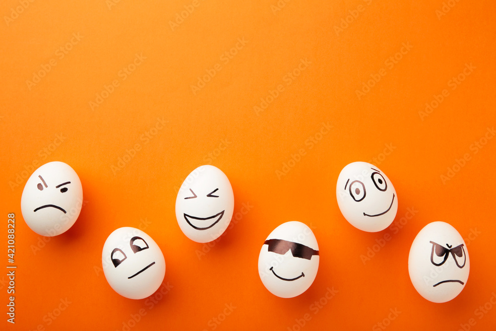 Funny Easter eggs with different emotions on his face on orange background. Easter composition. Funny Easter eggs with different emotions on his face on orange background. Easter composition.