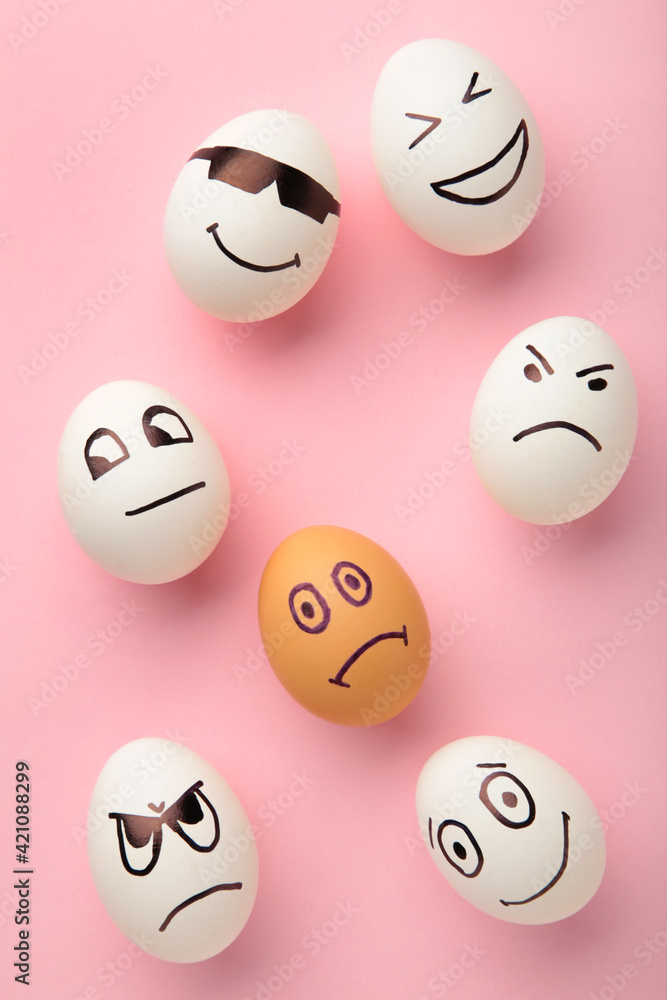 Eggs with different emotions on his face. Easter composition with copy space on pink background. Theme of racism and intolerance in society. Eggs with different emotions on his face. Easter composition with copy space on pink background. Theme of racism and intolerance in society.
