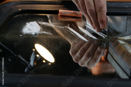 Cocaine addict cutting lines of white powder with a credit card. Illicit drug trafficking, illegal business. Habit, drug addiction. Close-up