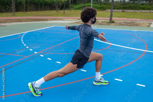 Young man stretching in a sports court yard in a park © Fran Martínez