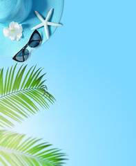 Tropical summer beach background. Palm trees branches, hat with starfish on blue summer background. Travel. Summer concept.