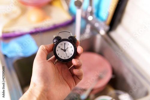 washing dishes at kitchen sink while doing cleaning at home during Staying at home. alarm clock selective focus