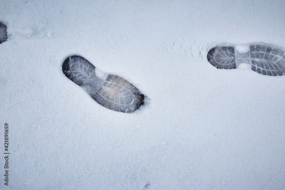 Shoe marks in melting snow against the background of asphalt pavement Shoe marks in melting snow against the background of asphalt pavement