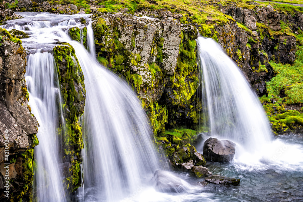 Fototapeta premium Grundarfjordur, Iceland Kirkjufell waterfall closeup smooth long exposure water on Snaefellsnes peninsula with green grass in summer