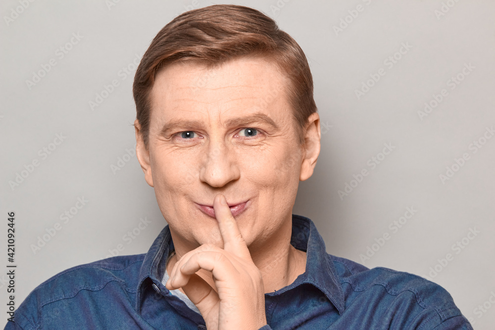 Portrait of happy man showing silence gesture with finger over lips Portrait of happy man showing silence gesture with finger over lips