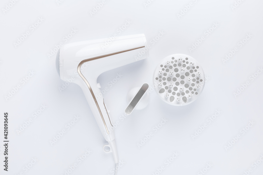 Hairdryer for drying hair with a diffuse and flat nozzle for styling on a white background. Top view. Hairdryer for drying hair with a diffuse and flat nozzle for styling on a white background. Top view.