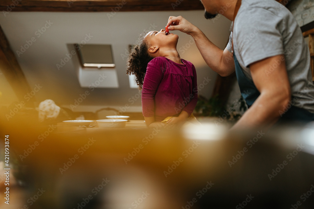 Father feeding his daughter in the kitchen