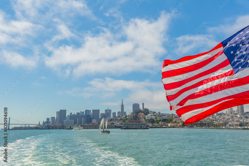 Naklejka premium San Francisco, California, United States - August 14, 2016: Alcatraz tour to Alcatraz island by boat trip in San Francisco Bay. Ferry boat and American flag waving in San Francisco pier with cityscape