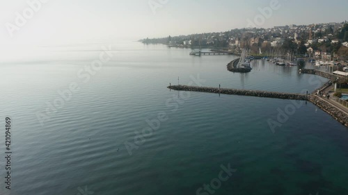 Flying over woman standing on end of quay in beautiful coastal city