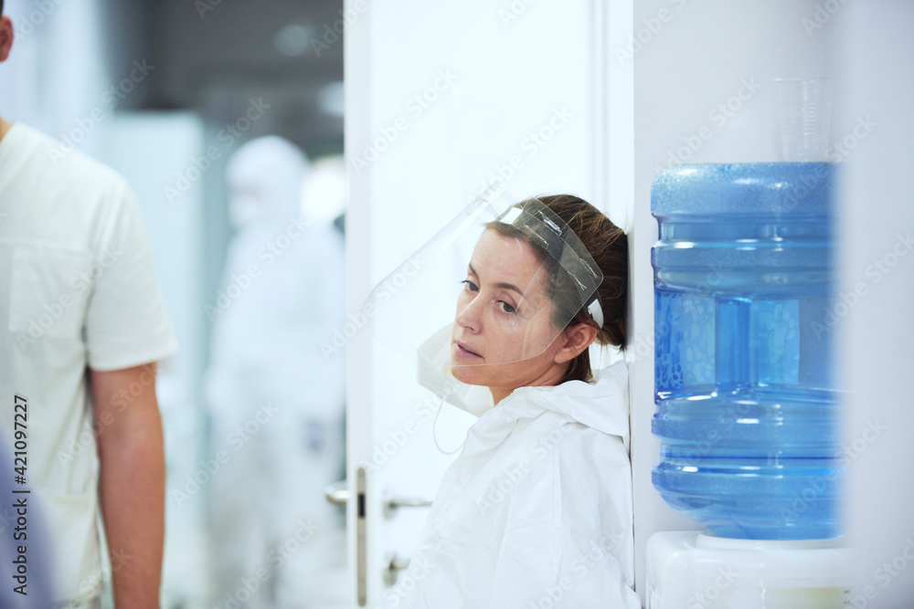 Obraz premium Female doctor in protective mask sitting in the corridor after operation