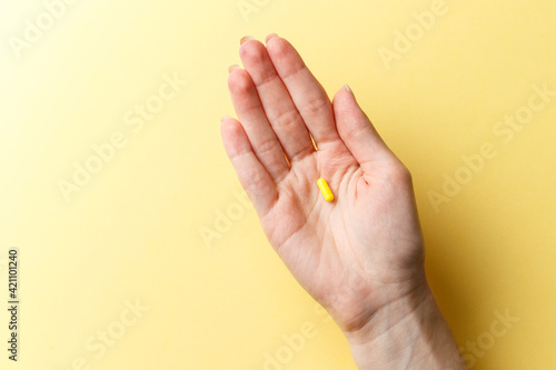 Colorful pills and tablets in the woman hand on colorful yellow background. Top view. Flat lay. Copy space. Medicine concept. Minimalistic abstract concept. Yellow medicine capsule