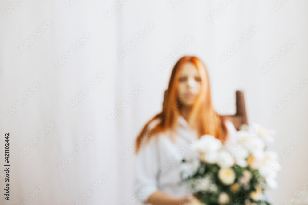 blurred portrait teenage girl in denim shorts and a white shirt stands with a bouquet of flowers in a studio decorated with retro-style flowers, a concept of spring and floral compositions