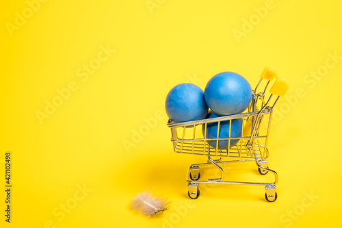 Supermarket trolley with three blue easter eggs
