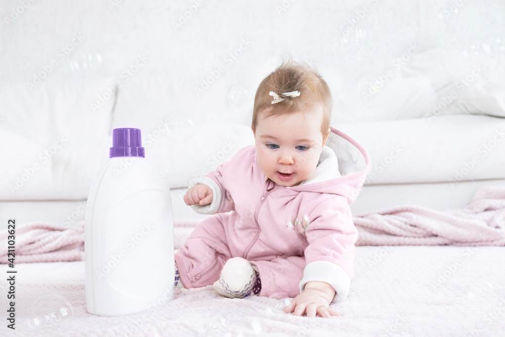 Adorable baby girl sitting on the floor near washing gel Adorable baby girl sitting on the floor near washing gel