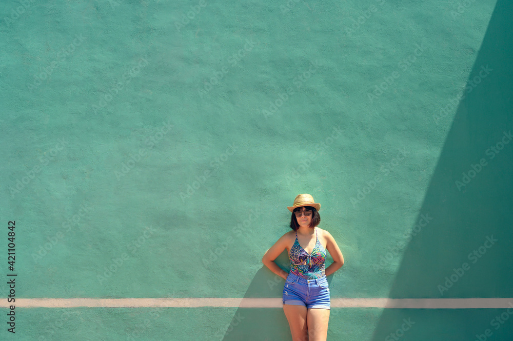 Portrait of a pretty young woman front of a training wall on a tennis court. Outdoor portrait of caucasian woman with sunglasses.