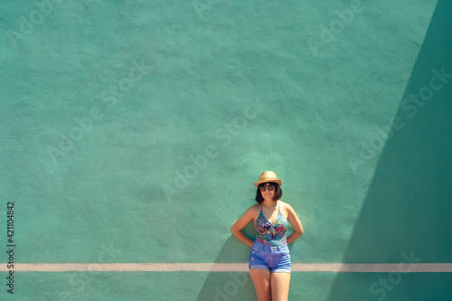 Portrait of a pretty young woman front of a training wall on a tennis court. Outdoor portrait of caucasian woman with sunglasses.