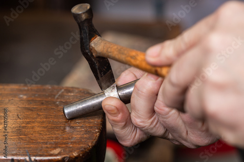 Fotografia, Obraz foreground, hammer hammering a silver ring to shape it in a jewelry workshop