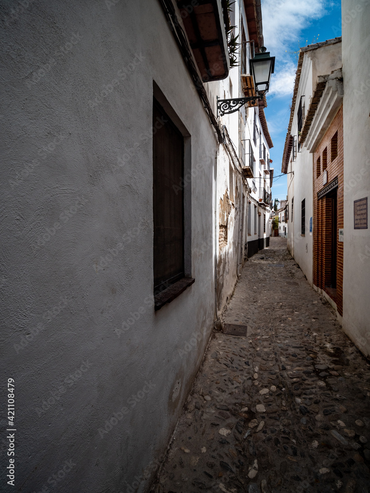 narrow street in the old town of Granada with Old Albaicin buildings, Spain