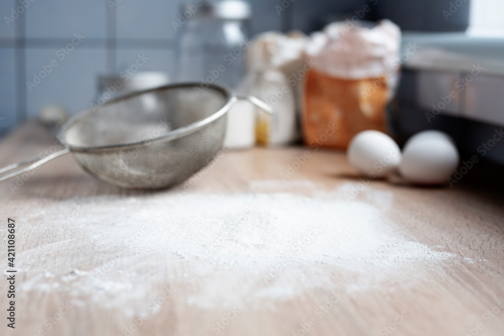 Wheat flour sprinkled on a wooden table in the kitchen with a sieve, cooking at home. Wheat flour sprinkled on a wooden table in the kitchen with a sieve, cooking at home.