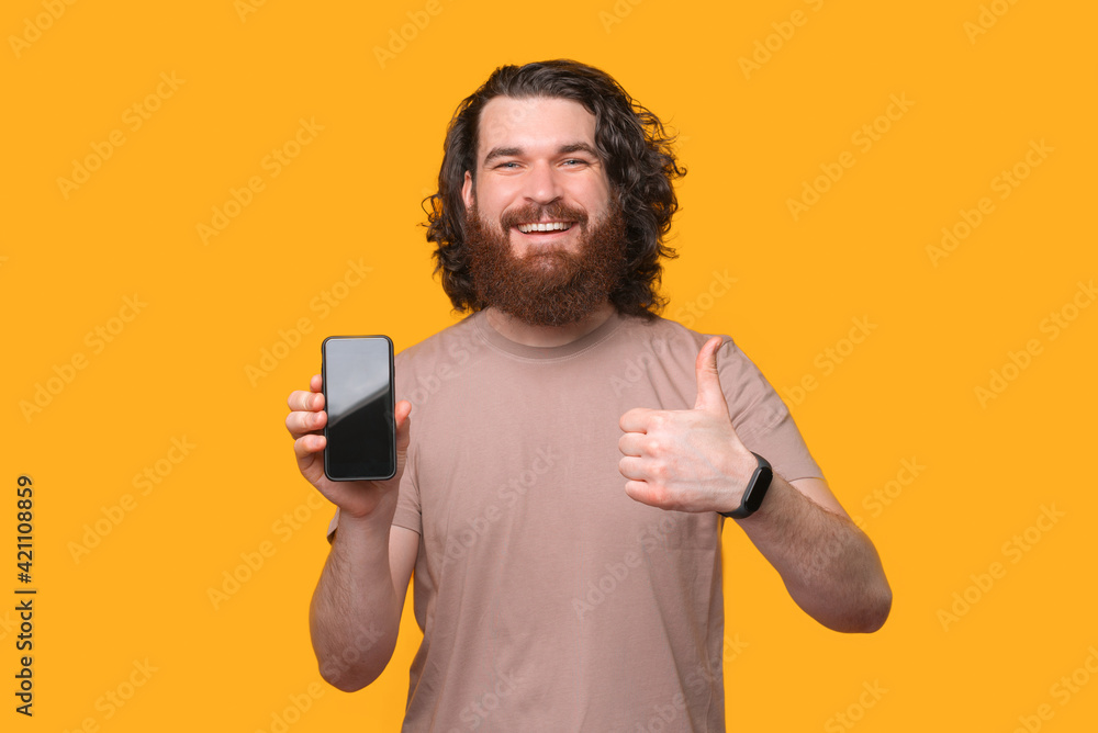This is a good choice, smiling bearded hipster man showing thumb up and smartphone This is a good choice, smiling bearded hipster man showing thumb up and smartphone