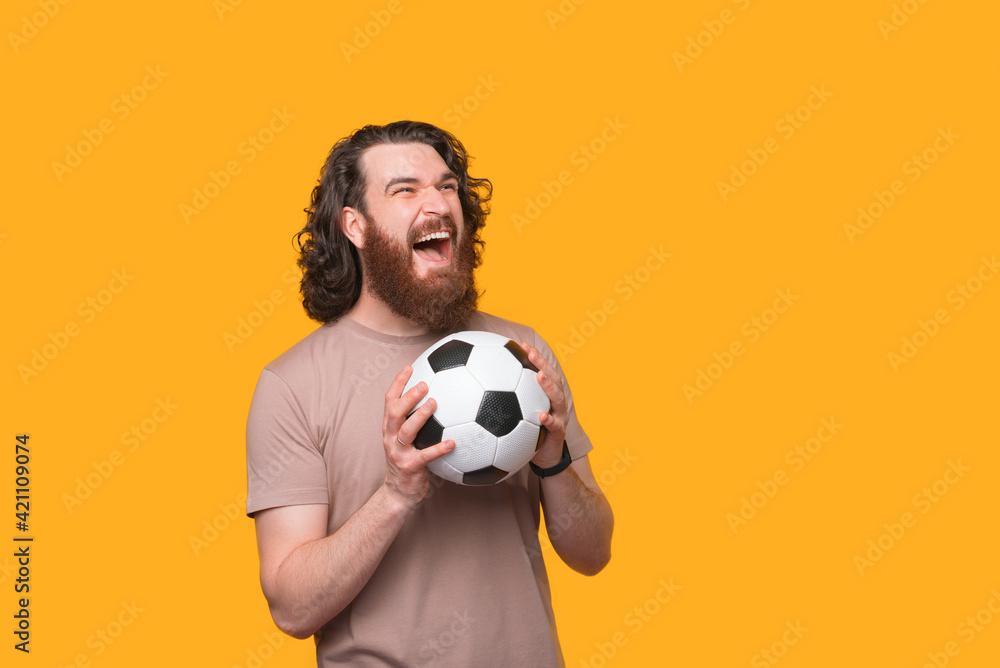 Amazed screaming bearded man holding soccer ball and supporting team Amazed screaming bearded man holding soccer ball and supporting team