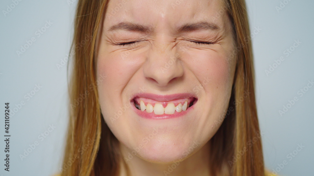 Closeup cheerful woman making funny faces on grey background in studio. Closeup cheerful woman making funny faces on grey background in studio.