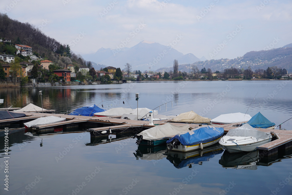 boats in the harbor and colorful houses on the shore of lake Lugano, Ticino