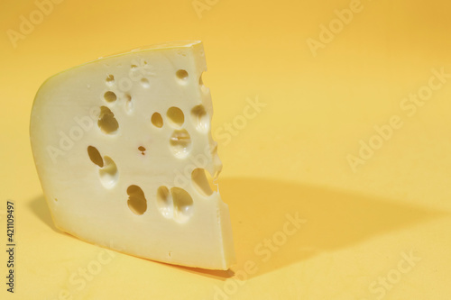 Close-up of gruyere cheese isolated on yellow background.